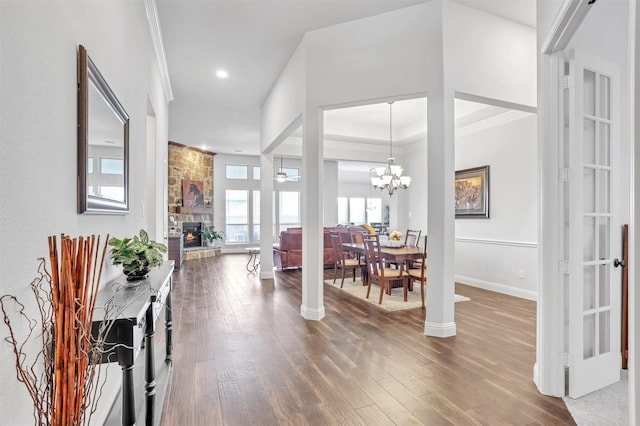 interior space with decorative columns, ceiling fan with notable chandelier, crown molding, wood-type flooring, and a fireplace