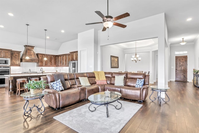 living room featuring ceiling fan with notable chandelier, dark hardwood / wood-style flooring, crown molding, and vaulted ceiling