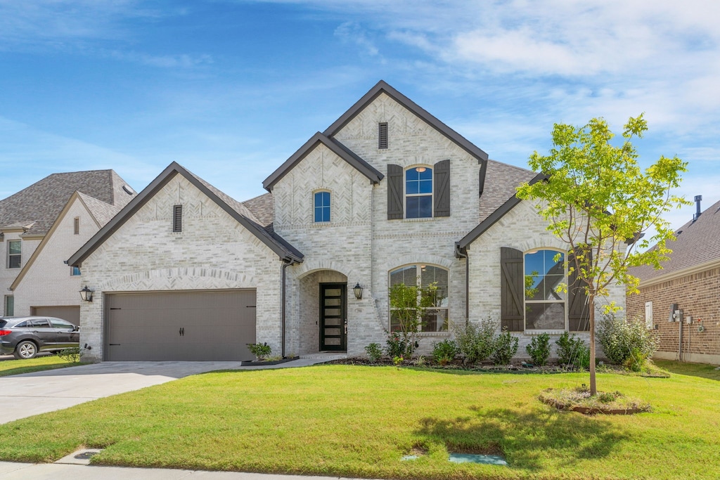 french country home featuring a garage and a front yard