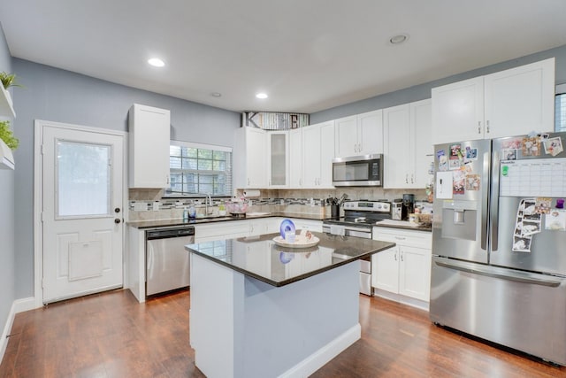 kitchen featuring appliances with stainless steel finishes, backsplash, white cabinets, dark hardwood / wood-style floors, and a kitchen island