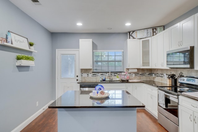 kitchen featuring appliances with stainless steel finishes, a center island, white cabinetry, and plenty of natural light