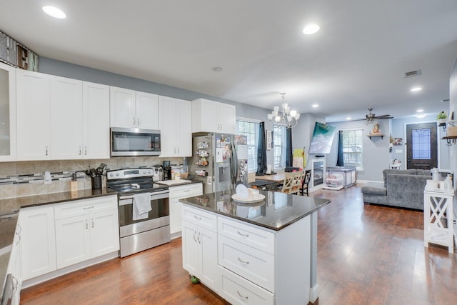 kitchen featuring dark wood-type flooring, white cabinets, ceiling fan with notable chandelier, tasteful backsplash, and stainless steel appliances