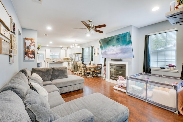 living room with wood-type flooring and ceiling fan with notable chandelier