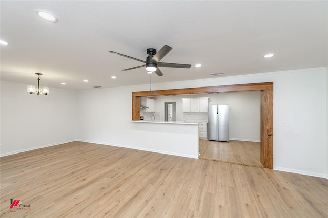 unfurnished living room featuring ceiling fan with notable chandelier, light hardwood / wood-style floors, and ornamental molding