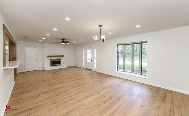 unfurnished living room with a fireplace, light hardwood / wood-style floors, crown molding, and ceiling fan with notable chandelier