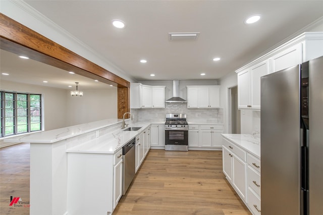 kitchen with sink, wall chimney exhaust hood, kitchen peninsula, light hardwood / wood-style floors, and appliances with stainless steel finishes