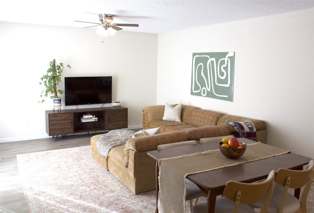 living room featuring ceiling fan, hardwood / wood-style floors, and a textured ceiling