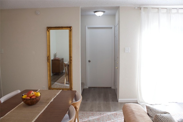 hallway with light hardwood / wood-style floors and a textured ceiling