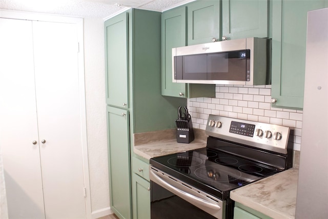 kitchen with green cabinets, decorative backsplash, and stainless steel appliances