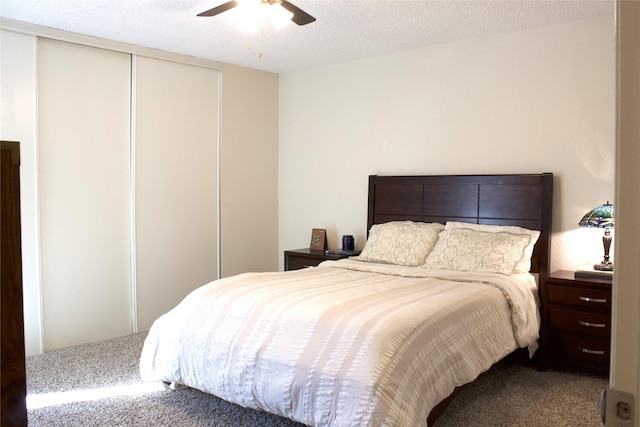 carpeted bedroom with ceiling fan, a closet, and a textured ceiling