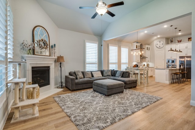 living room featuring ceiling fan, lofted ceiling, and light wood-type flooring