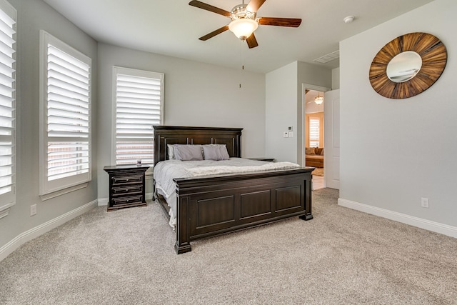 carpeted bedroom with ensuite bath and ceiling fan