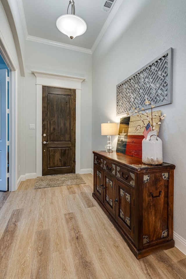 foyer featuring ornamental molding and light hardwood / wood-style flooring