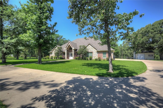 view of front of property with a garage, an outdoor structure, and a front lawn