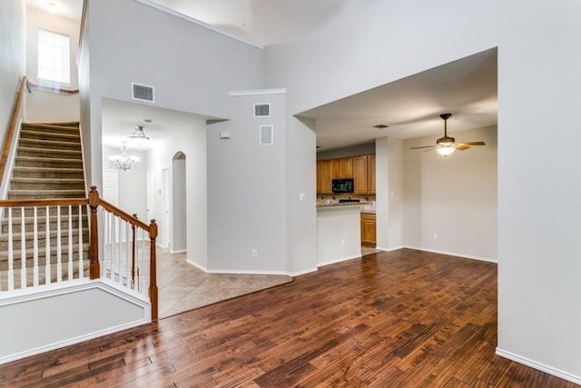 unfurnished living room with ceiling fan with notable chandelier and light hardwood / wood-style flooring