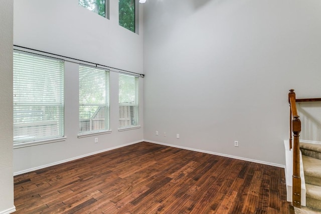 empty room with a towering ceiling and dark hardwood / wood-style flooring