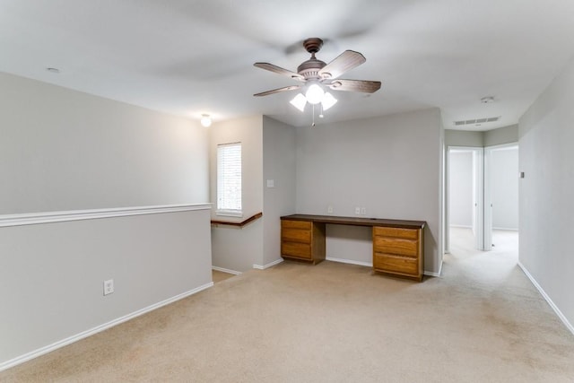 interior space featuring light carpet, built in desk, and ceiling fan