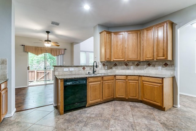 kitchen with backsplash, light stone counters, sink, and black dishwasher