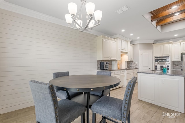 dining area with a chandelier, wooden walls, light hardwood / wood-style floors, and ornamental molding