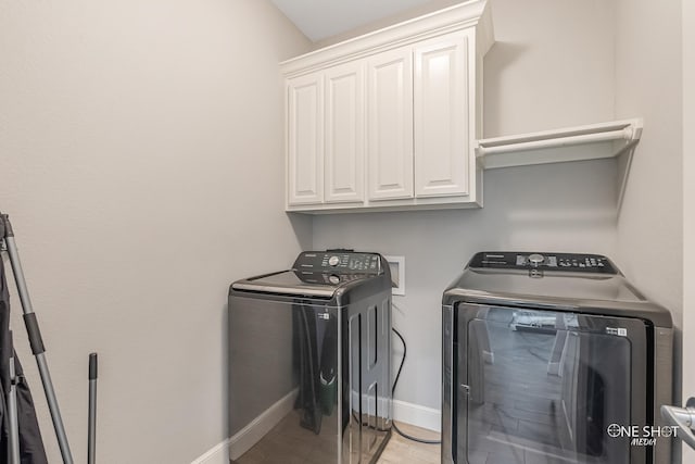 clothes washing area featuring cabinets and washer and dryer