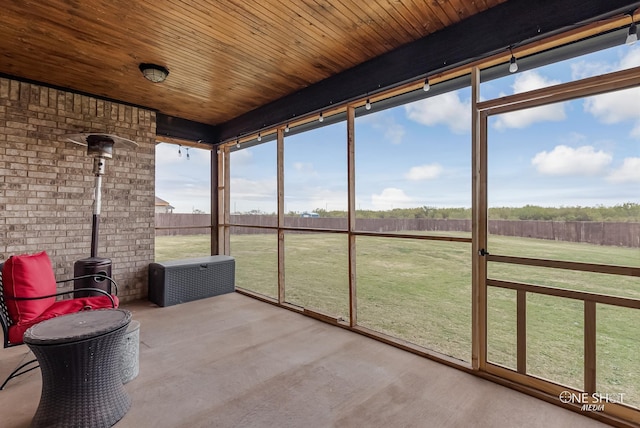 unfurnished sunroom with wood ceiling, a wood stove, and a rural view