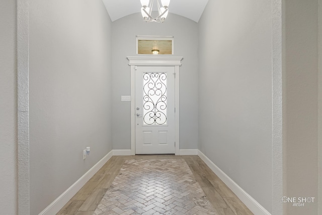 entrance foyer featuring light wood-type flooring, an inviting chandelier, and vaulted ceiling