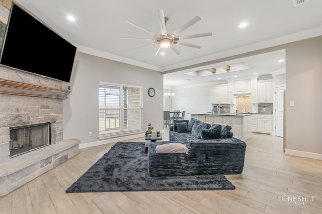 living room with a stone fireplace, crown molding, ceiling fan, and light hardwood / wood-style floors