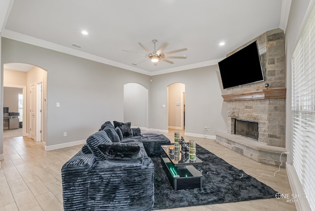 living room featuring ceiling fan, ornamental molding, a fireplace, and light hardwood / wood-style flooring