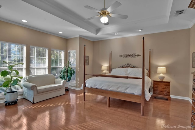 bedroom featuring hardwood / wood-style flooring, crown molding, ceiling fan, and a tray ceiling