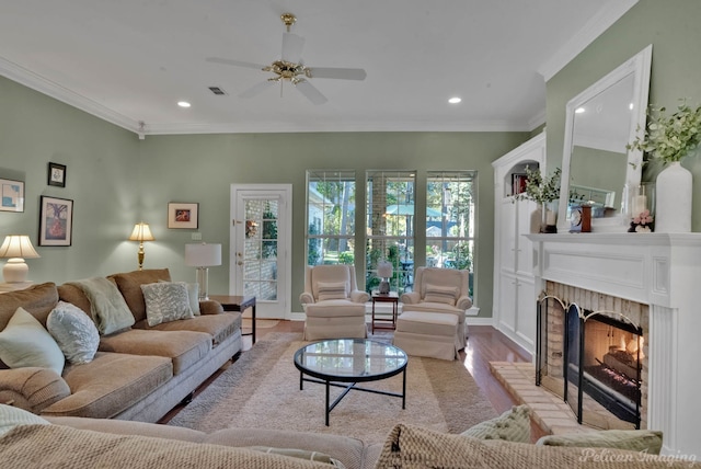 living room with ceiling fan, light hardwood / wood-style floors, crown molding, and a brick fireplace