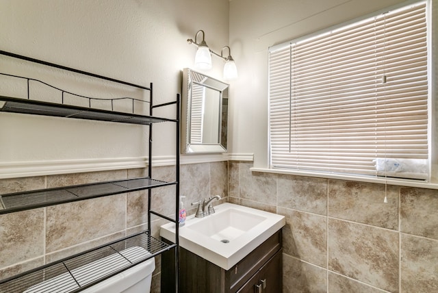 bathroom with vanity, toilet, and tile walls