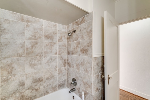 bathroom with hardwood / wood-style flooring and tiled shower / bath