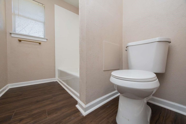 bathroom with hardwood / wood-style floors, a tub, and toilet