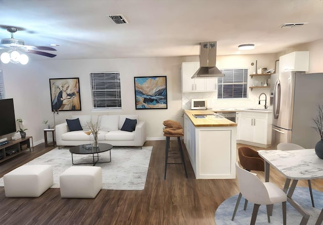 kitchen featuring dark wood-type flooring, tasteful backsplash, stainless steel fridge with ice dispenser, island exhaust hood, and white cabinets