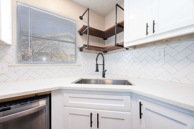 kitchen with white cabinets, decorative backsplash, stainless steel dishwasher, and sink