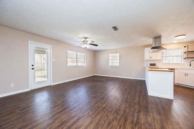 kitchen with island range hood, dark hardwood / wood-style floors, white cabinets, ceiling fan, and backsplash