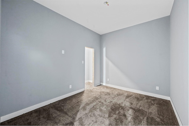 carpeted spare room featuring vaulted ceiling