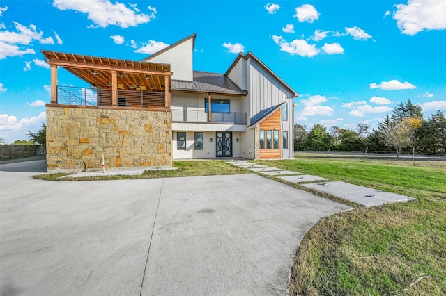 rear view of house featuring a lawn and a balcony