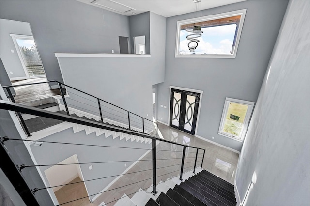 staircase with tile patterned floors, a towering ceiling, and french doors