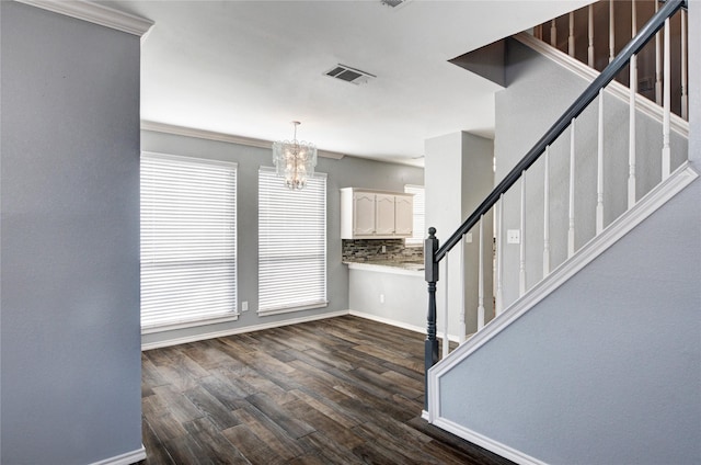 foyer featuring dark hardwood / wood-style flooring, an inviting chandelier, and ornamental molding