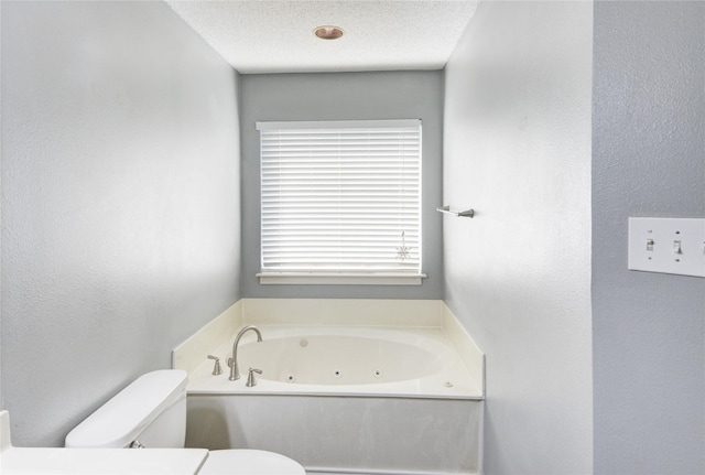 bathroom featuring a textured ceiling, toilet, and a tub