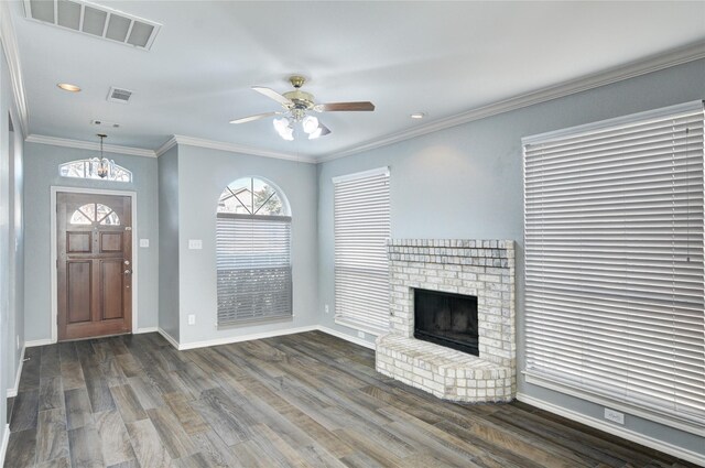 unfurnished living room with a fireplace, dark wood-type flooring, ceiling fan with notable chandelier, and ornamental molding