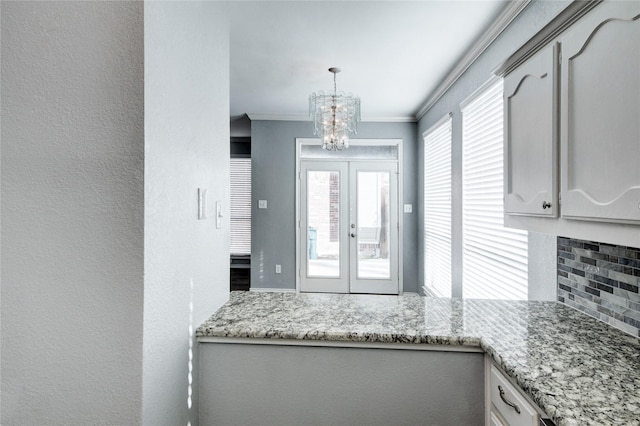 interior space featuring pendant lighting, an inviting chandelier, white cabinets, crown molding, and tasteful backsplash