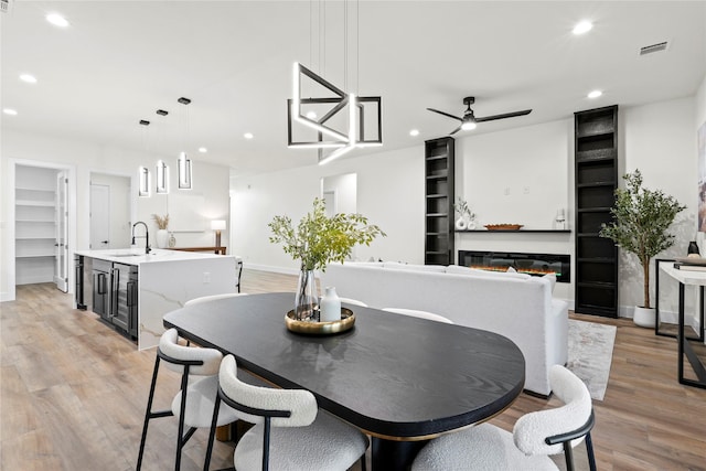 dining area with sink, light hardwood / wood-style flooring, ceiling fan, built in shelves, and beverage cooler