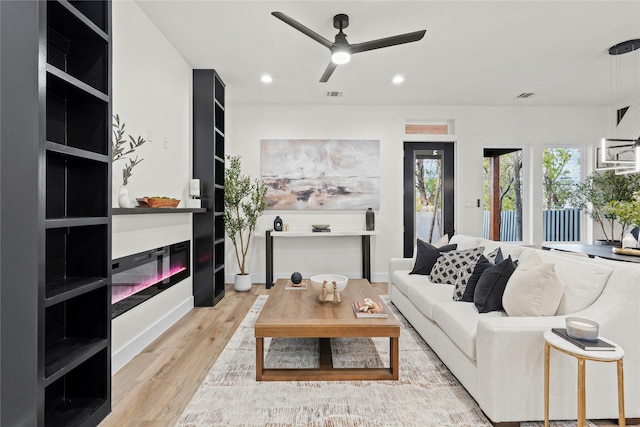 living room with ceiling fan and light hardwood / wood-style flooring