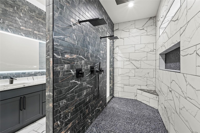 bathroom featuring vanity, a tile shower, and tile walls