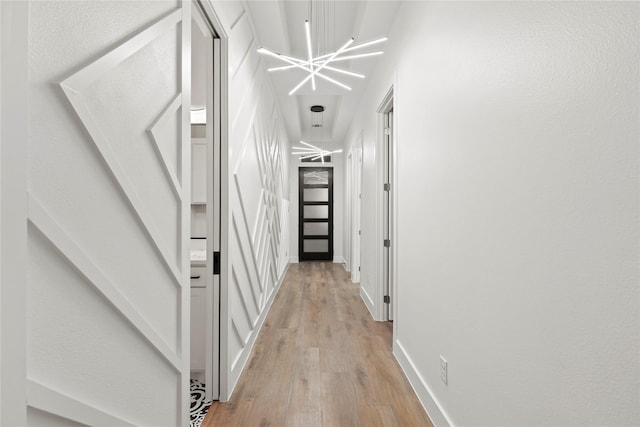 corridor featuring light wood-type flooring and a chandelier