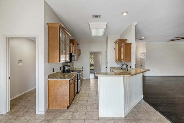 kitchen featuring light stone countertops, light tile patterned floors, stainless steel appliances, and kitchen peninsula