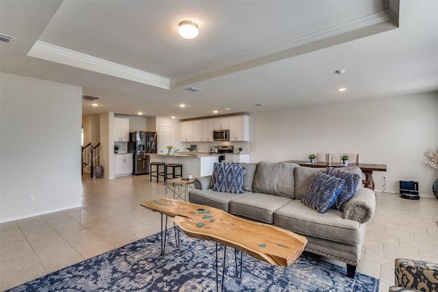 living room featuring a tray ceiling, light tile patterned floors, and ornamental molding