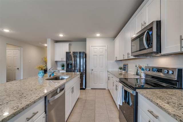 kitchen featuring sink, decorative backsplash, light stone countertops, white cabinetry, and stainless steel appliances